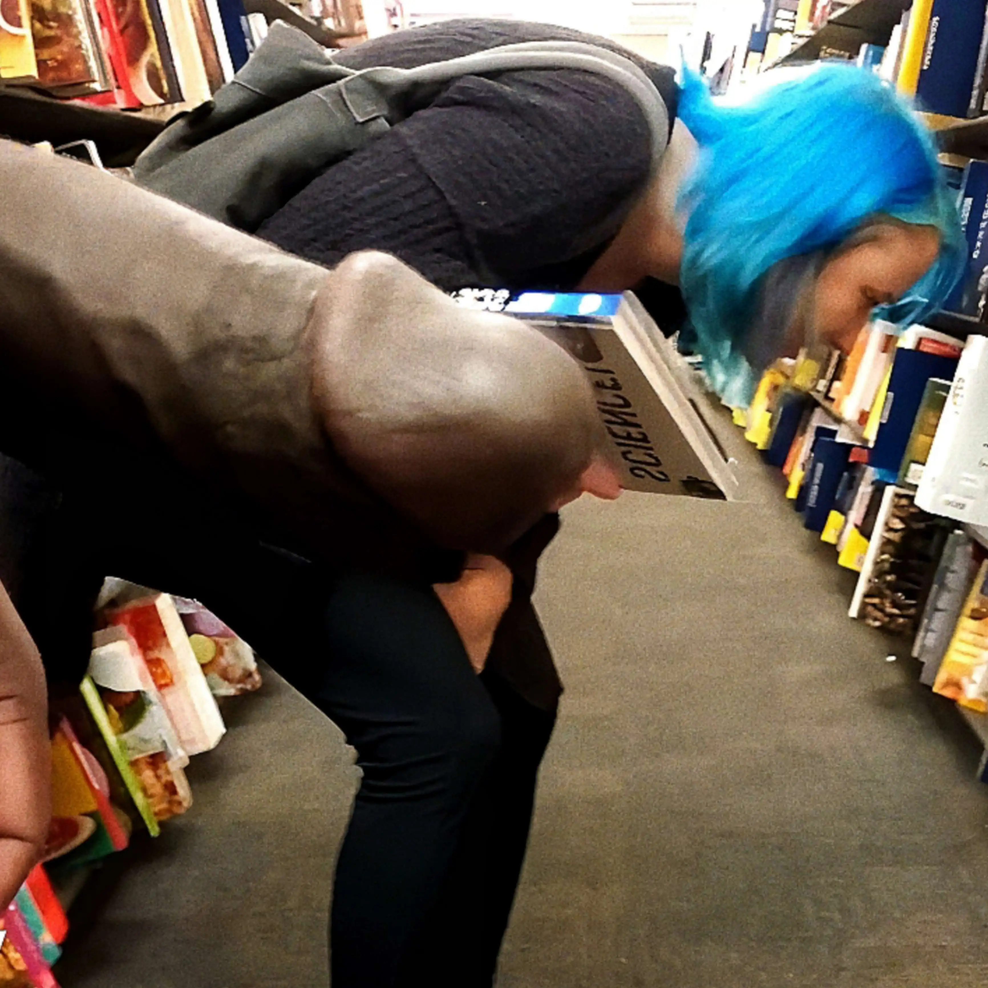 Hot blue haired girl looking at books in the library