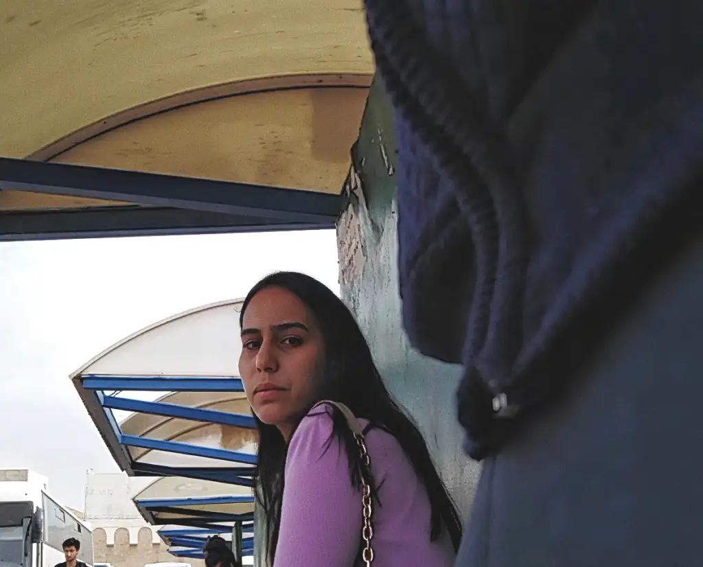 Beautiful brunette looking at the bulge flash at the bus stop