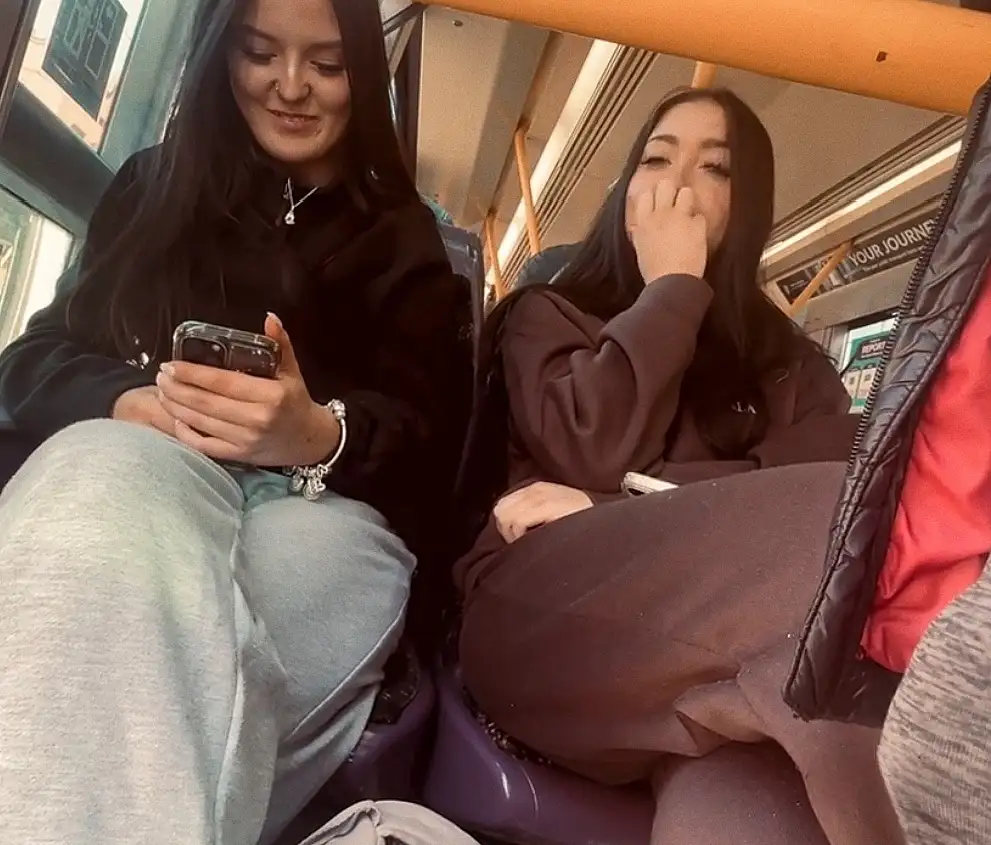 Naughty friends smiling and looking at bulge on the train
