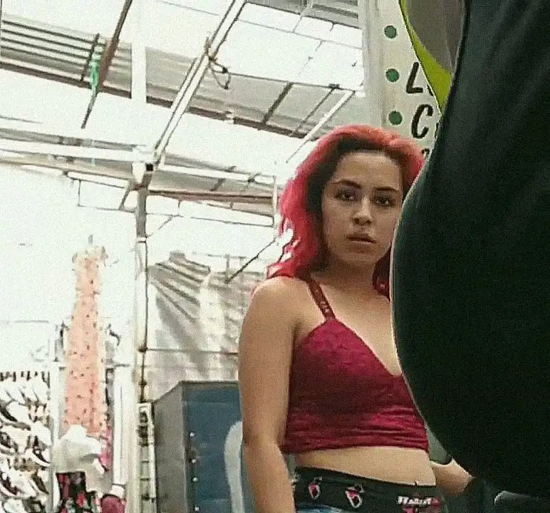Latina saleswoman pink hair looking at bulge 