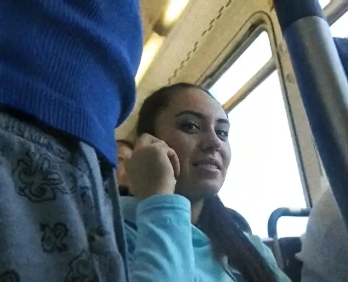 Talking on the phone with her boyfriend and looking at bulges on the bus